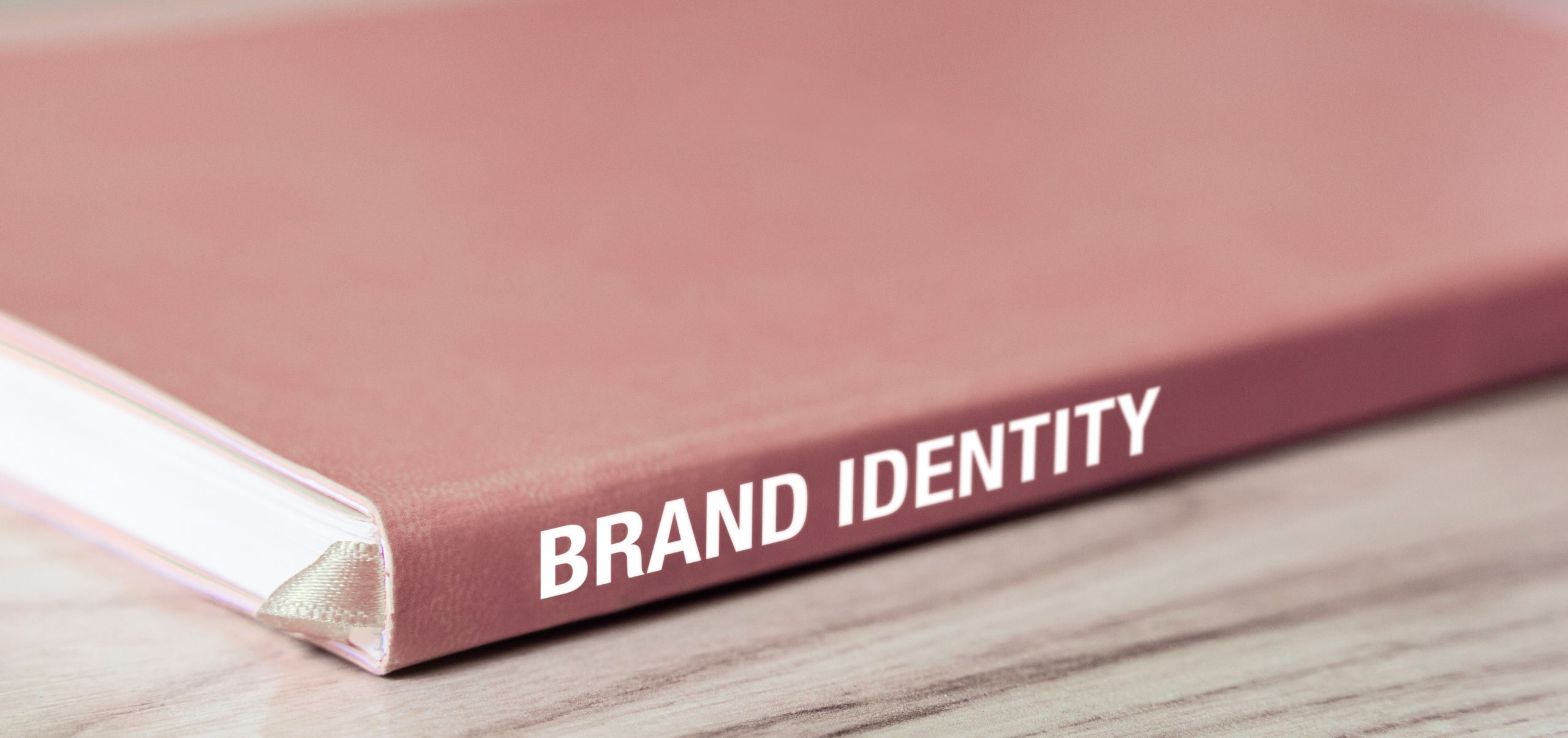 Pink book on a table labeled “Brand Identity,” highlighting the importance of defining brand elements
