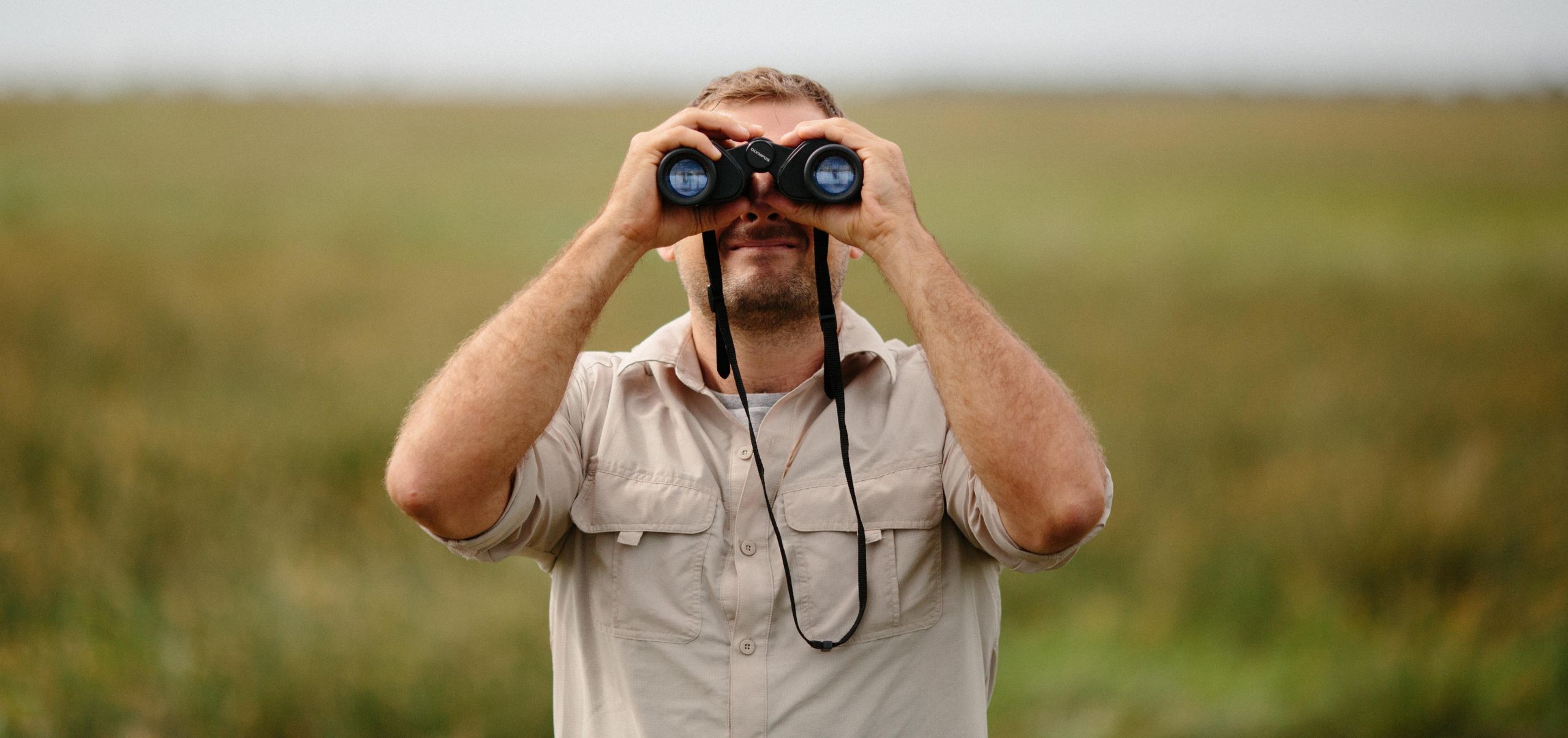 Person using binoculars outdoors, symbolizing looking ahead for opportunities