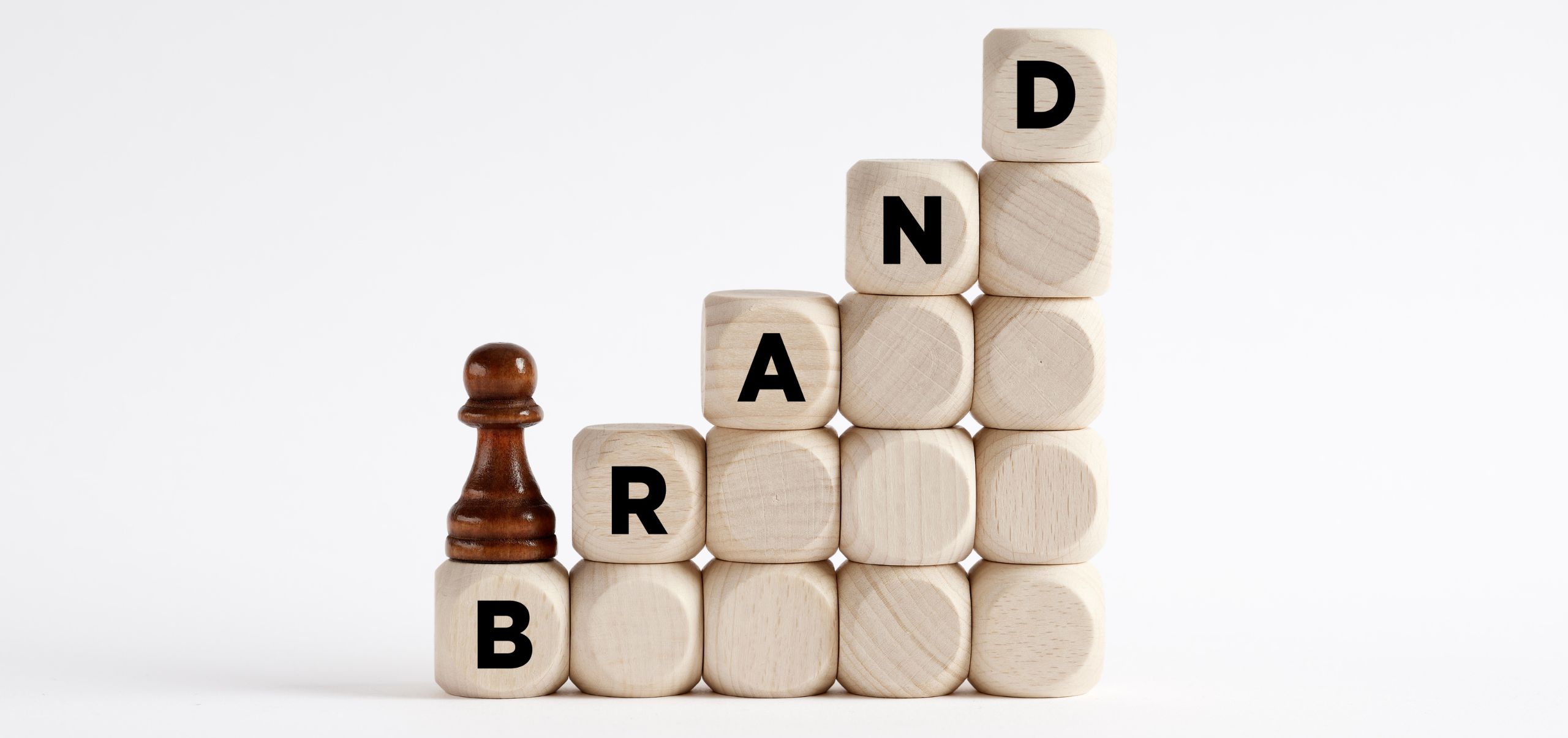 Blocks forming a ladder with each block spelling “Brand,” topped by a chess piece, symbolizing strategic steps in building a brand