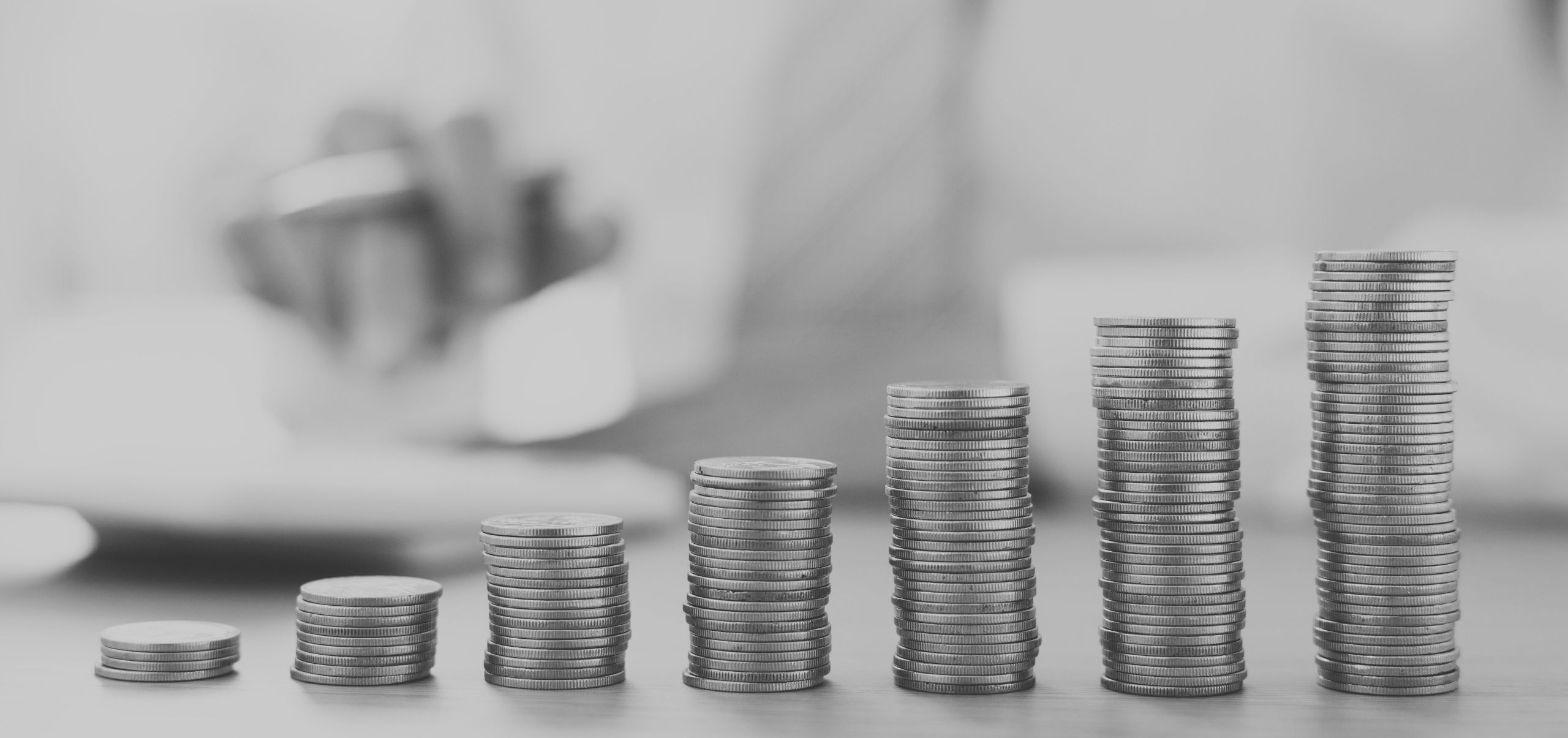 Coins arranged from small to large on a table, illustrating rising costs or expenses
