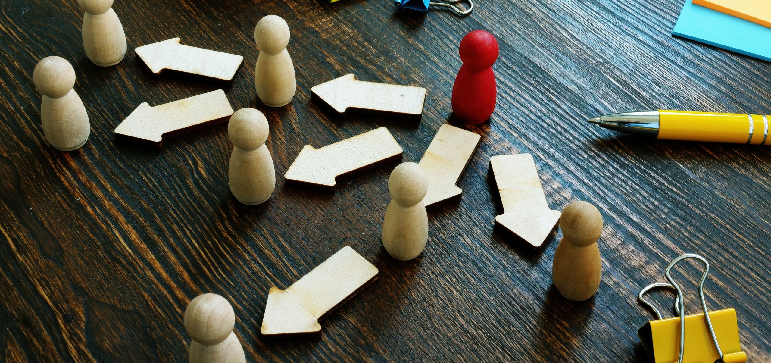 Wooden figures on a table showing task delegation from one person to another