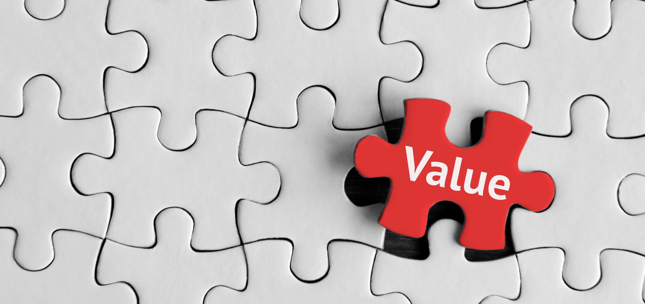 White puzzle pieces with one red piece labeled “Value,” symbolizing identifying unique brand value