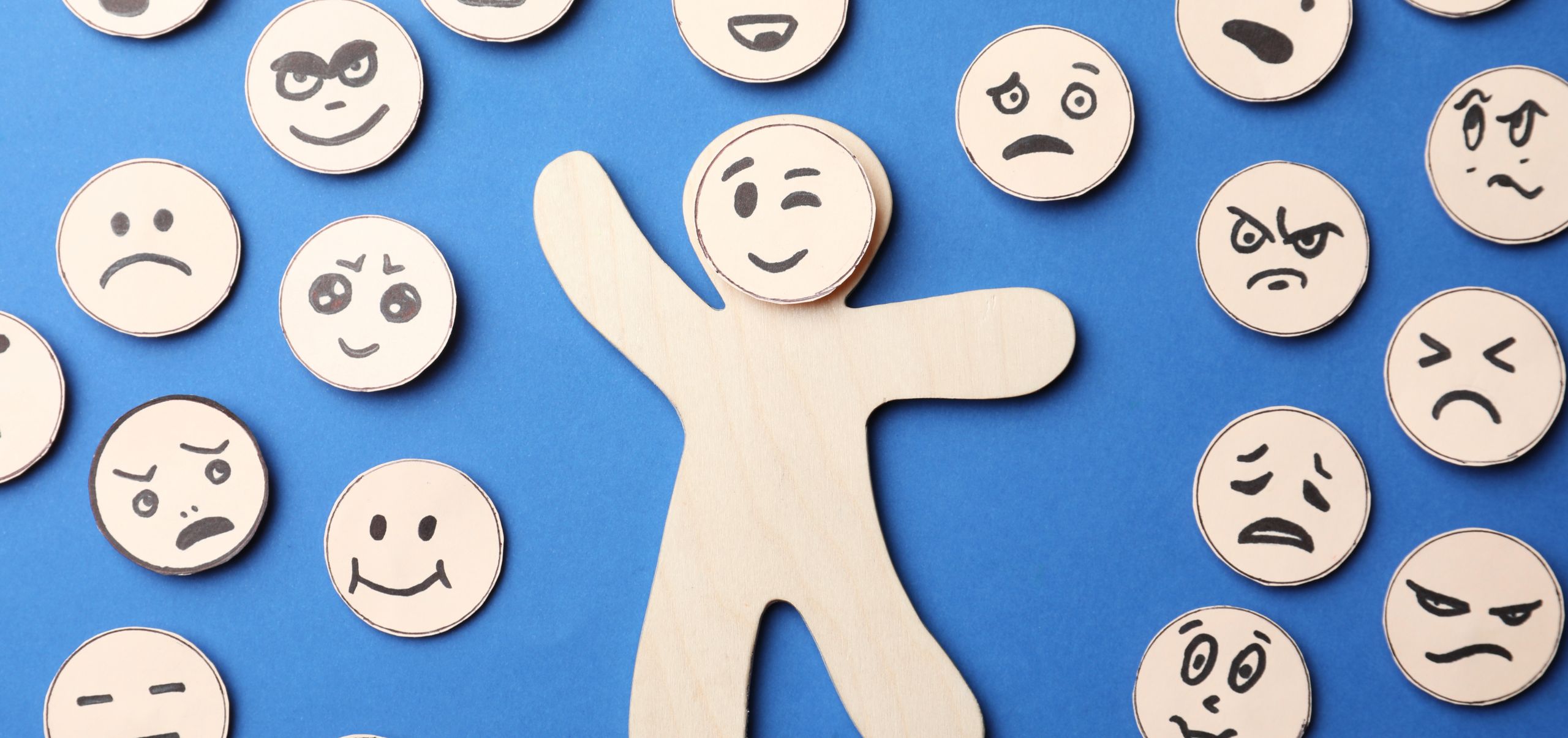 A paper figure with a smiling face among other emotions, representing emotional intelligence in people management