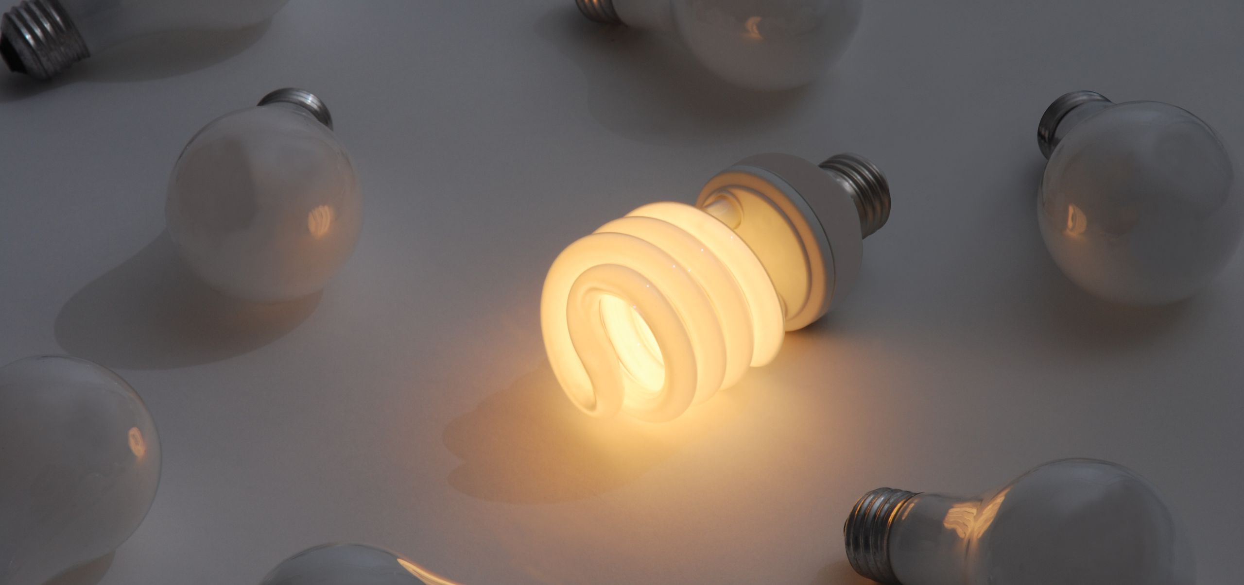 Bulbs on a table with only one lit in the center, representing energy efficiency