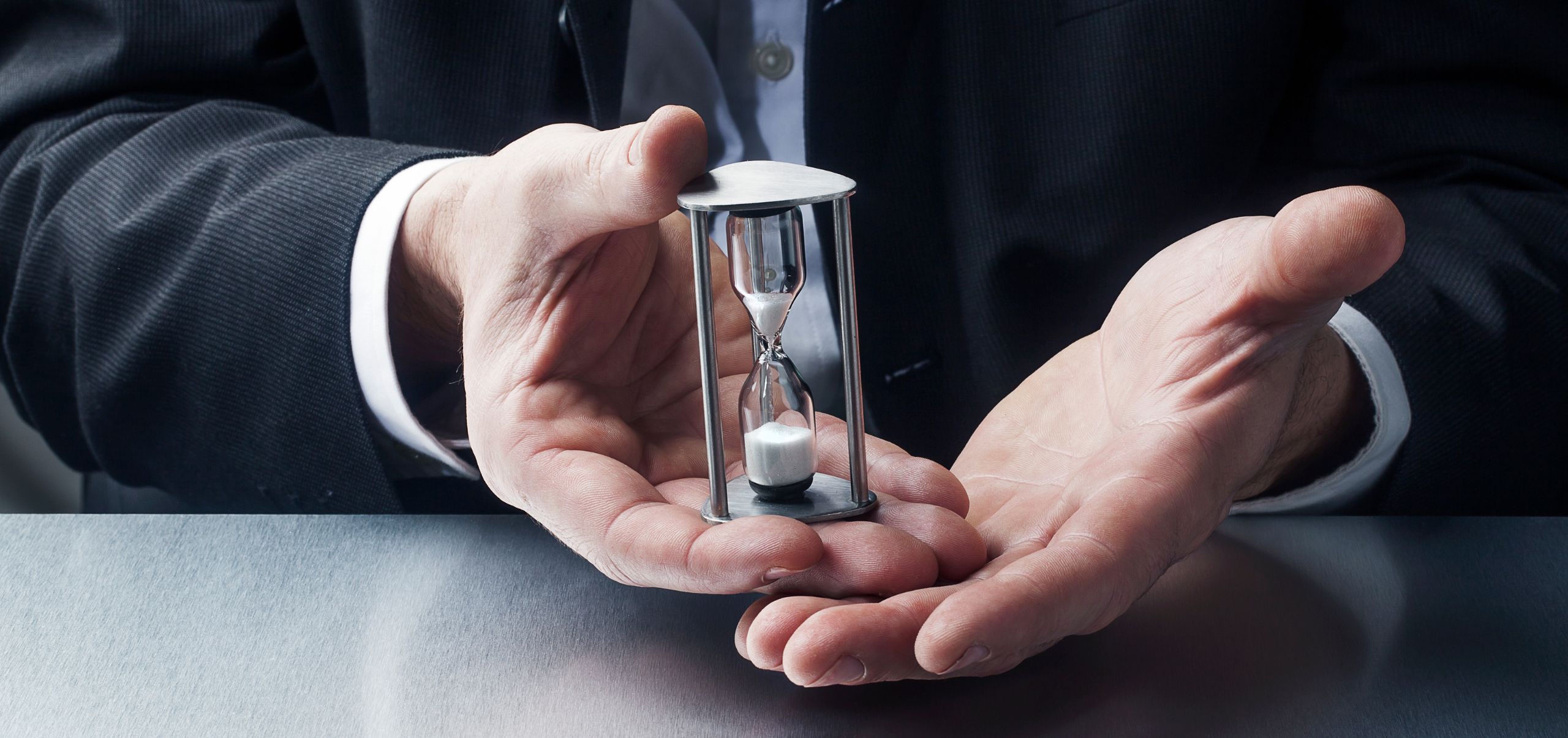 Person holding a small hourglass in their hands, representing time management