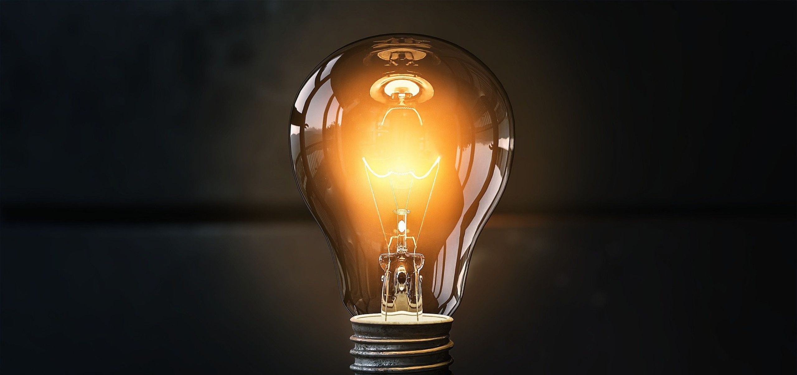 Single light bulb shining in a dim, shadowy space