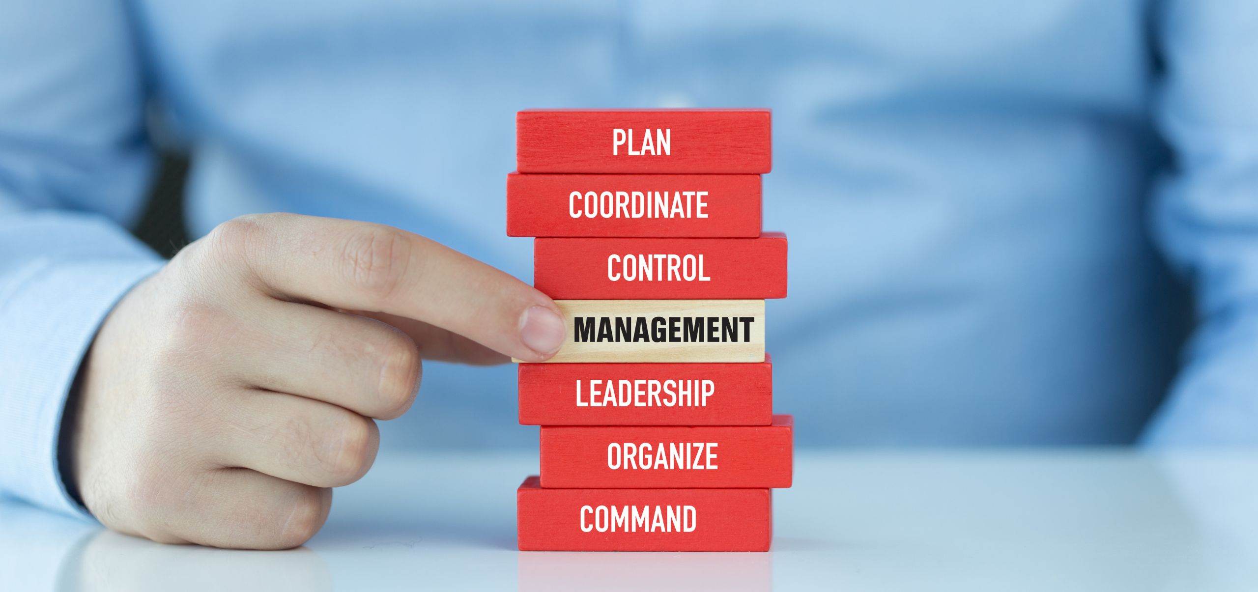 A person selecting a “Management” block among others, representing decision-making in leadership