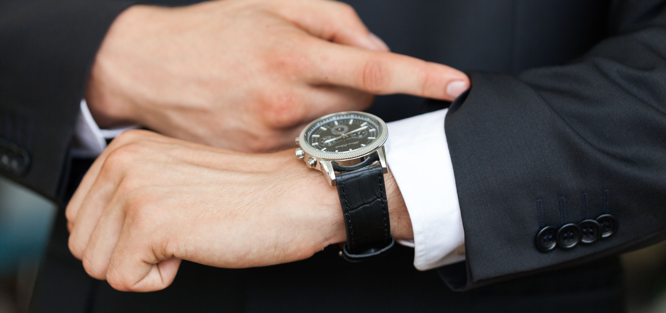 Person in a suit checking his watch, illustrating punctuality and effective time use
