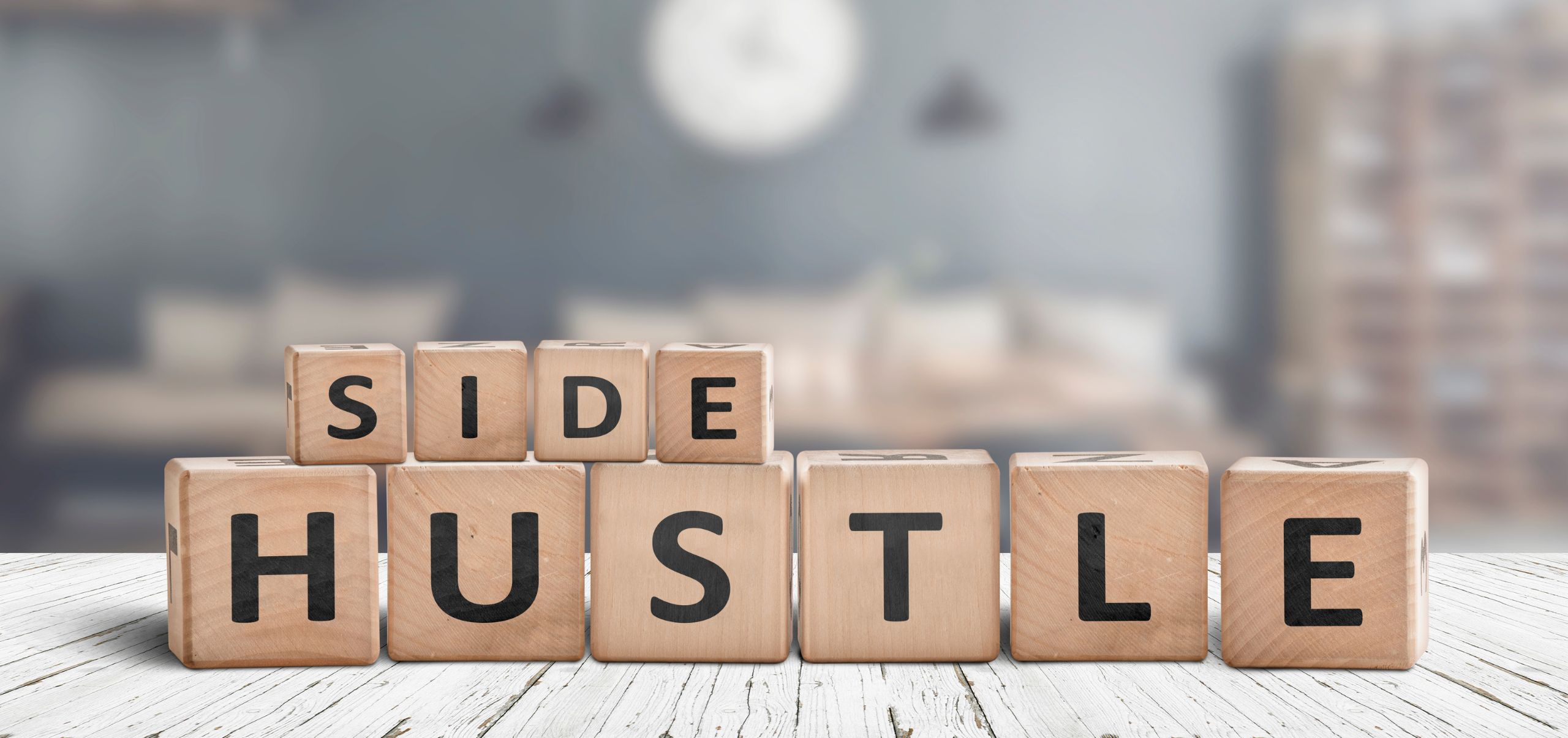 Blocks on a table arranged to spell “Side Hustle,” representing building a profitable side hustle