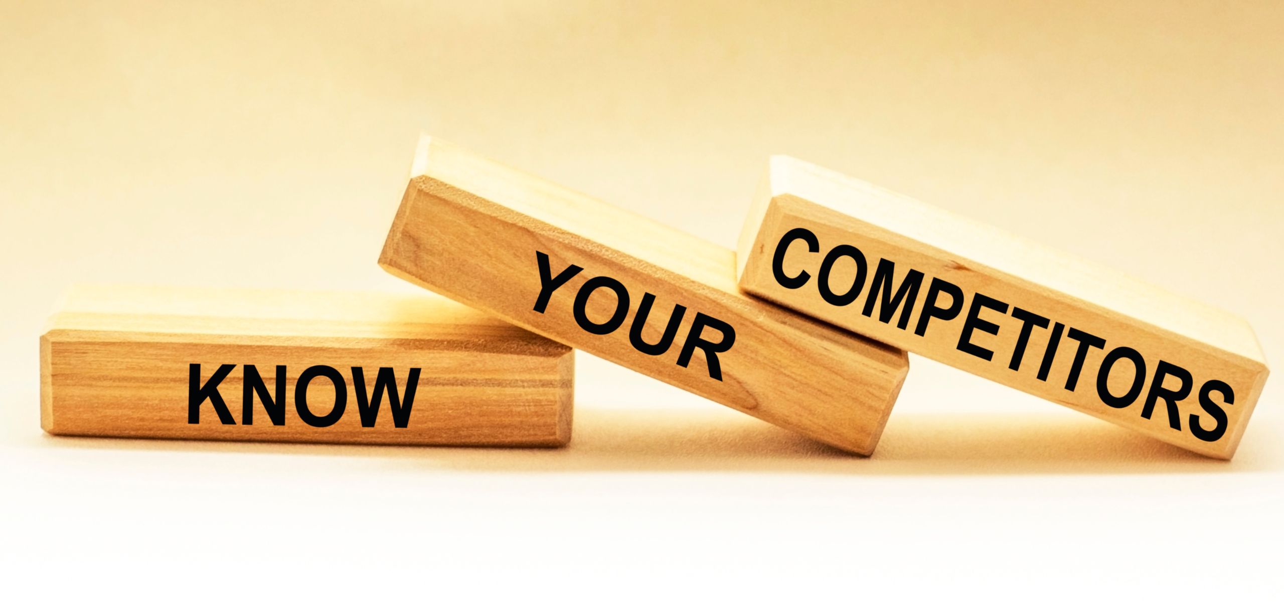 Three wooden blocks stacked in sequence know, your, competitors highlighting competitive research