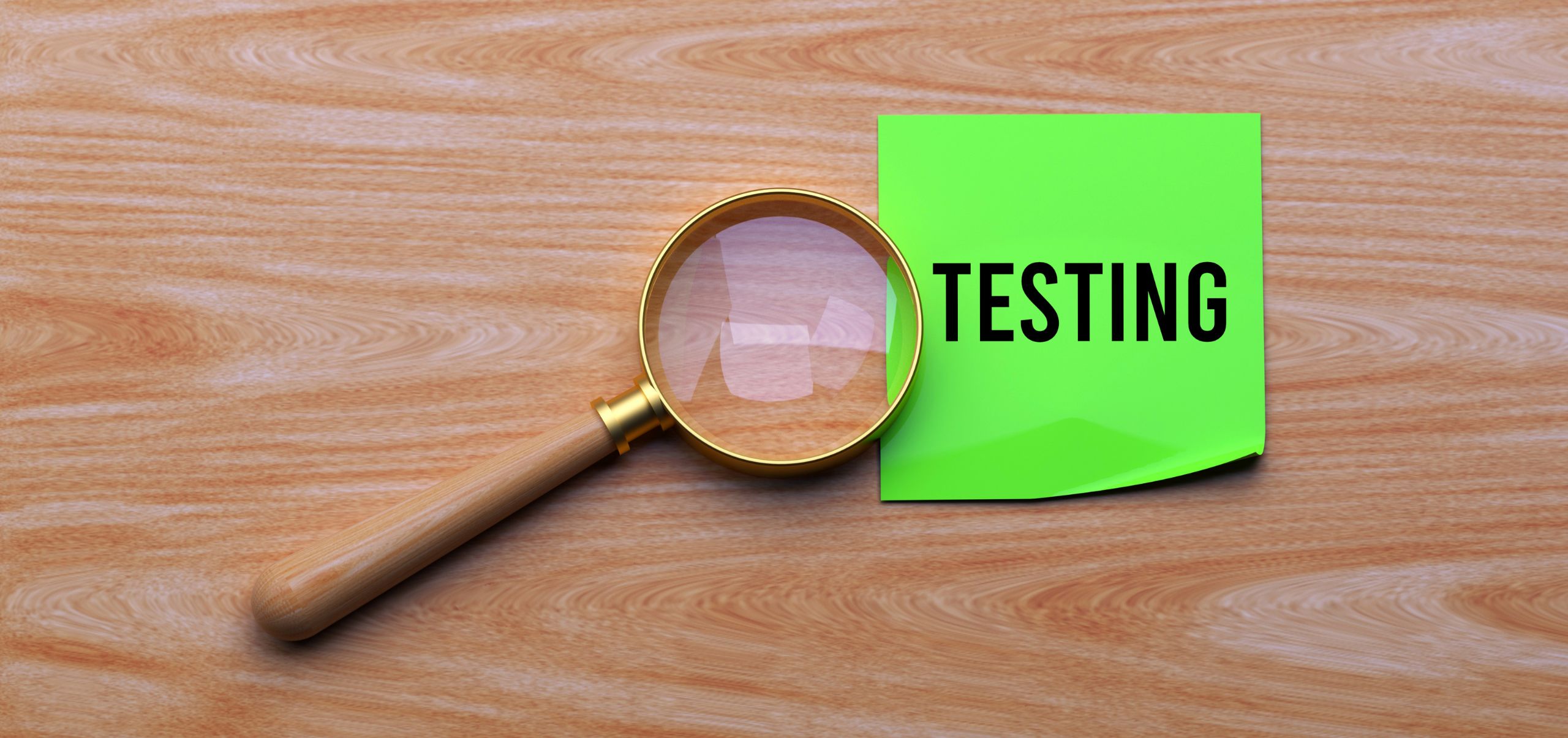 Green paper on a table with “Testing” written in black and a magnifying glass on top, representing email testing for performance