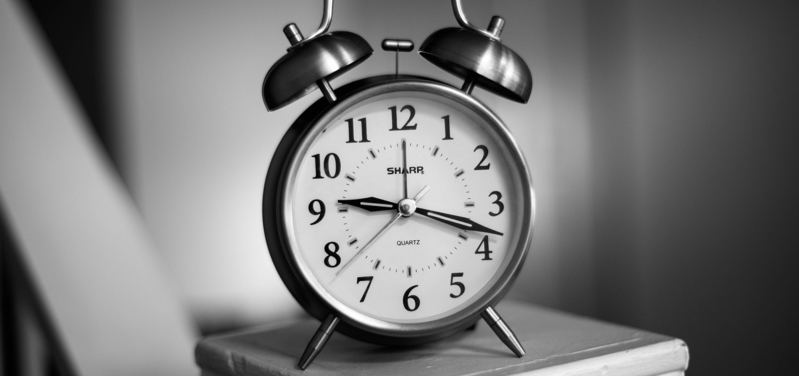 Clock placed on a book, representing time management skills essential for running a side hustle