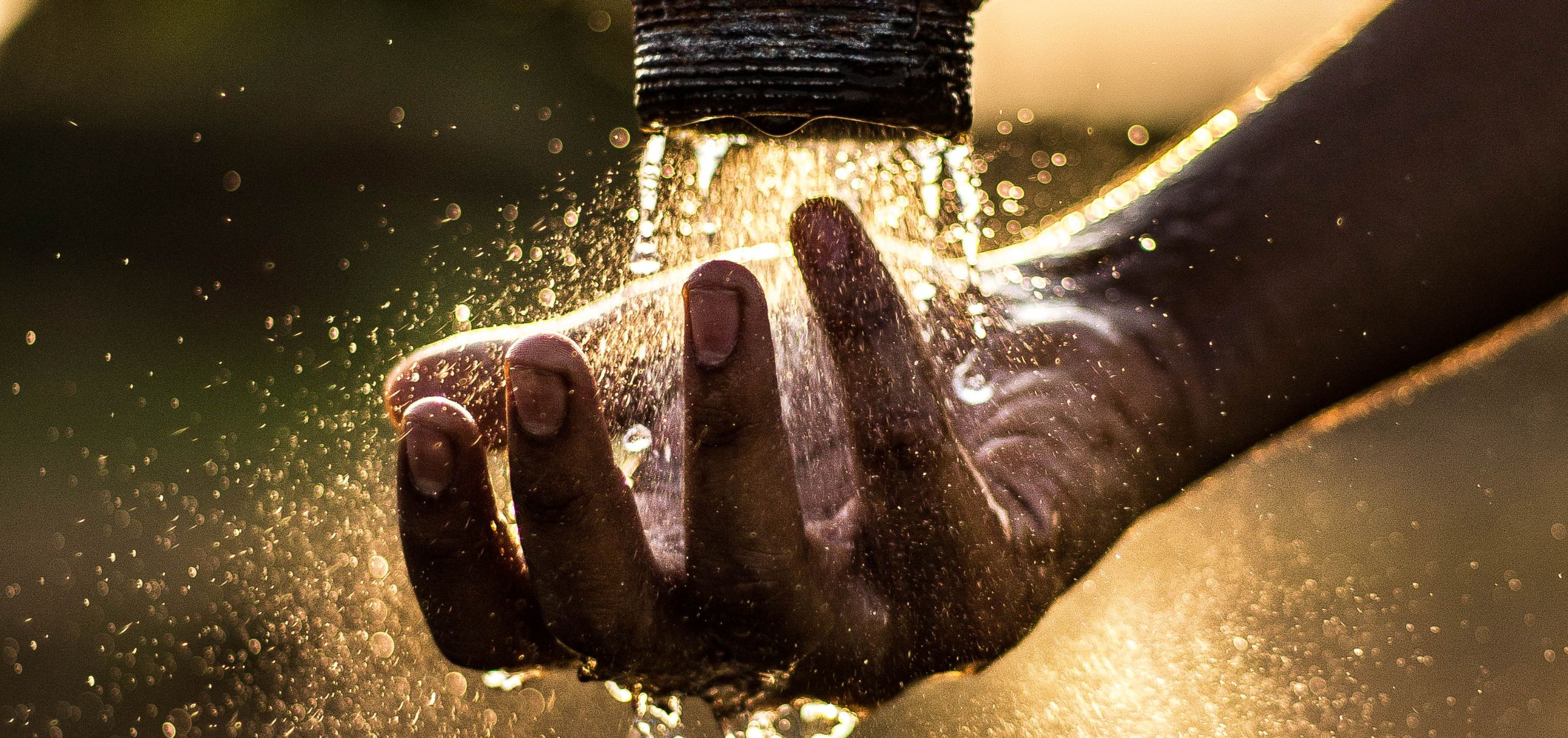 Person placing a hand under flowing water from a tube, representing water conservation